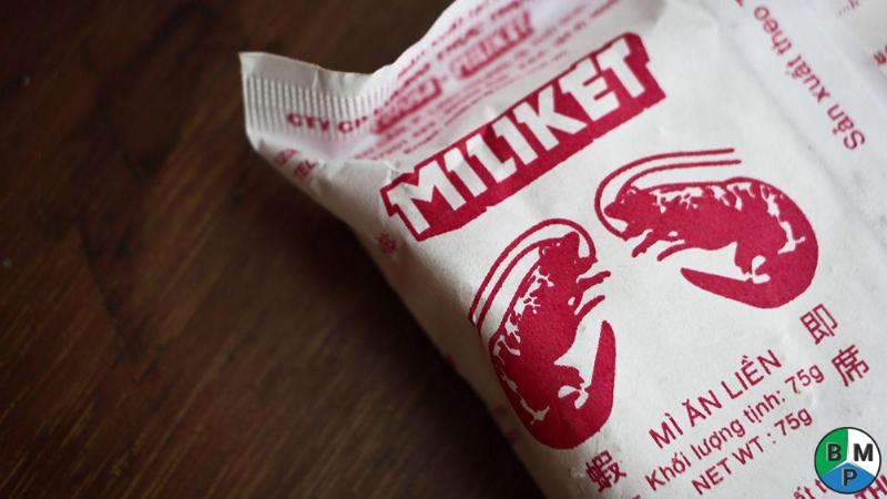 Hình ảnh một người đang so sánh giá hoặc khối lượng sản phẩm trong siêu thị, trên các nhãn mác có ghi khối lượng bằng gram và kilogram