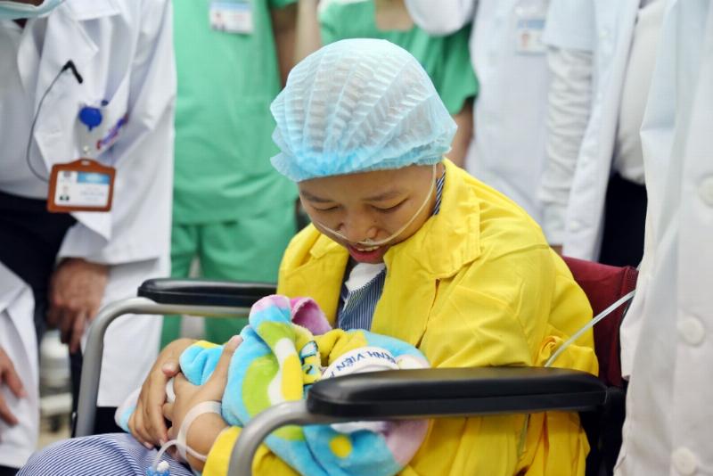 Một người mẹ đang ôm và mỉm cười với em bé sơ sinh của mình, cả hai đều trông khỏe mạnh và hạnh phúc, thể hiện kết quả của việc chăm sóc dinh dưỡng tốt cho cả mẹ và bé.