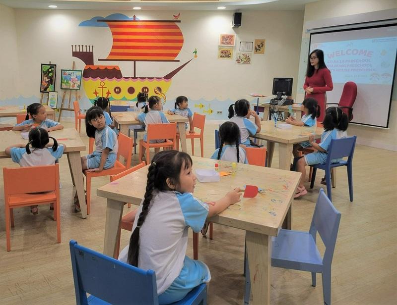 Hình ảnh trẻ em lớp 1 vui vẻ học tiếng Anh cùng giáo viên và các bạn, biểu tượng của việc học ngoại ngữ sớm và hiệu quả.