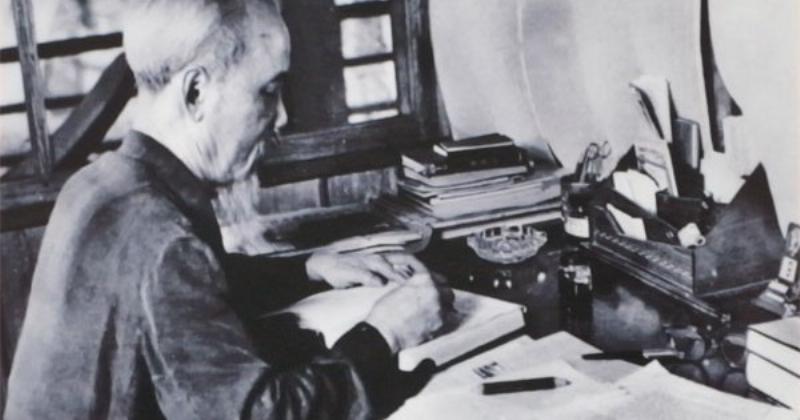 Một người đang ngồi viết dàn ý trên giấy, với cây bút và sổ ghi chép, xung quanh là những hình vẽ sơ lược về cây cối để minh họa